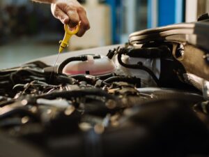 A person pulling out the oil dipstick to check the oil levels.