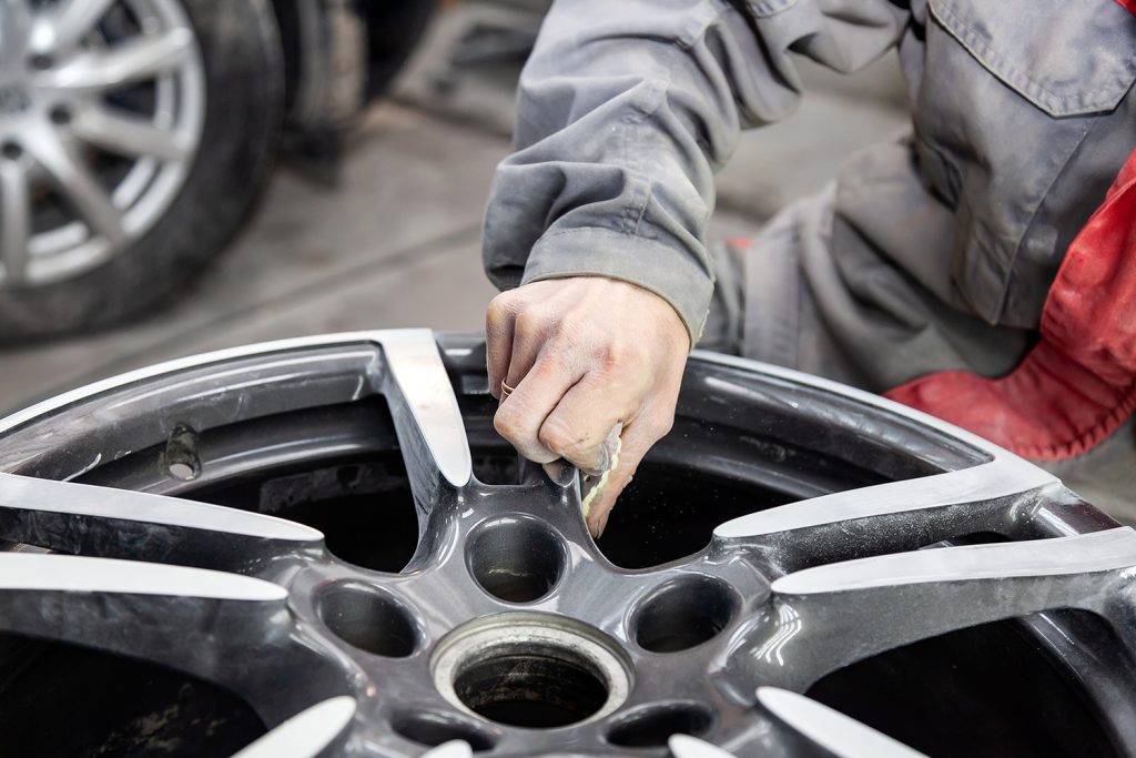 A wheel resting off of a car as it is polished and examined.