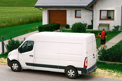 A white delivery van parked in front of a house.