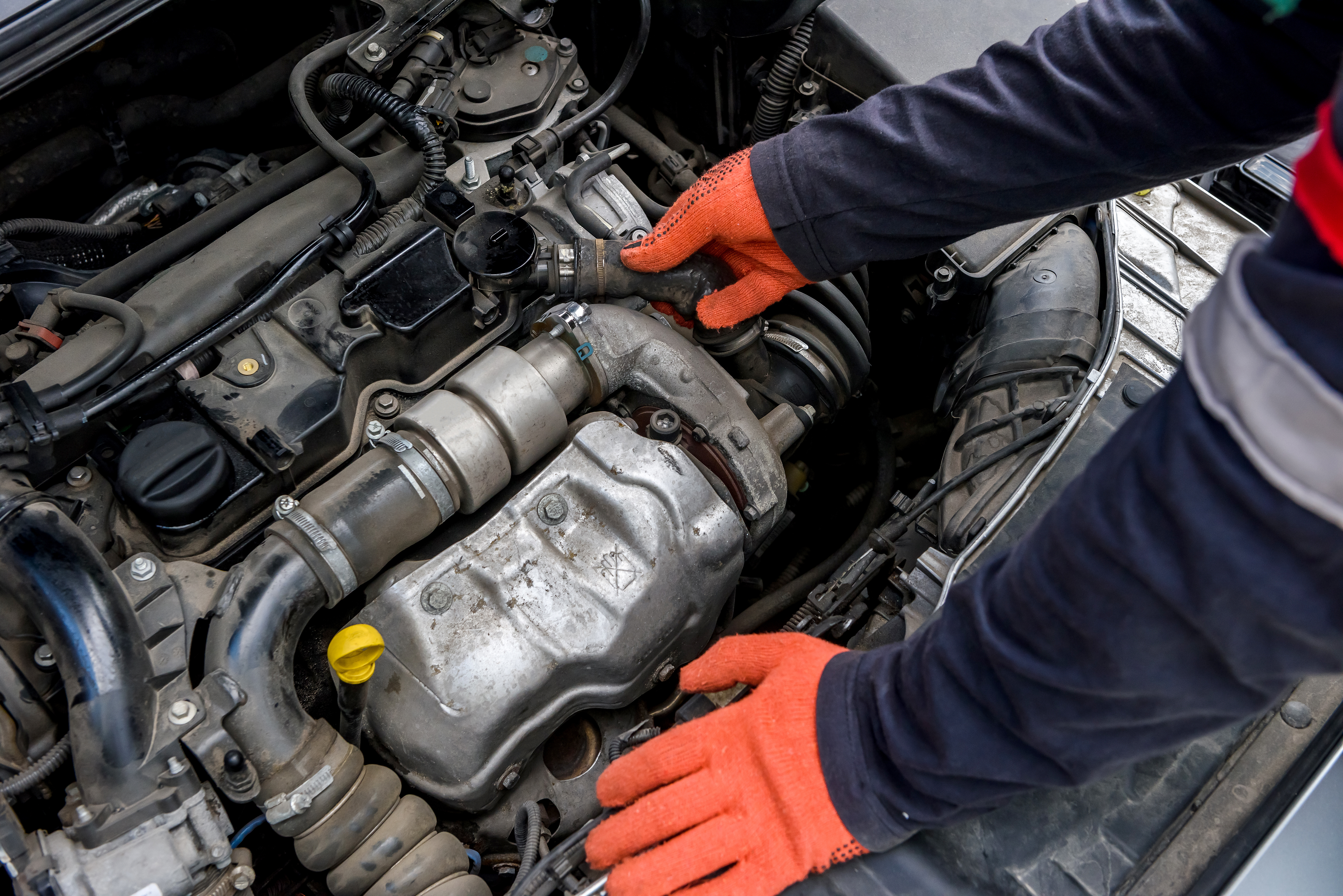 mechanic in protective gloves with car engine