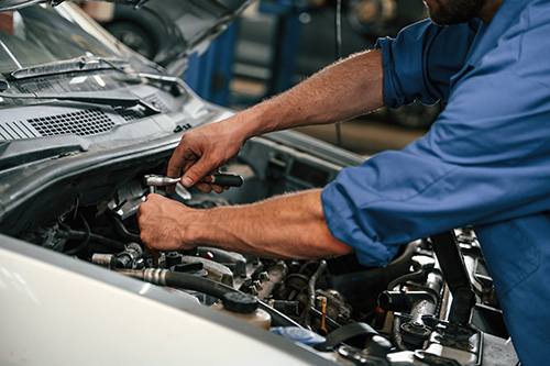 A mechanic working under the hood of a car.