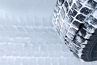 A tire compacted with snow driving over a snow-covered road.